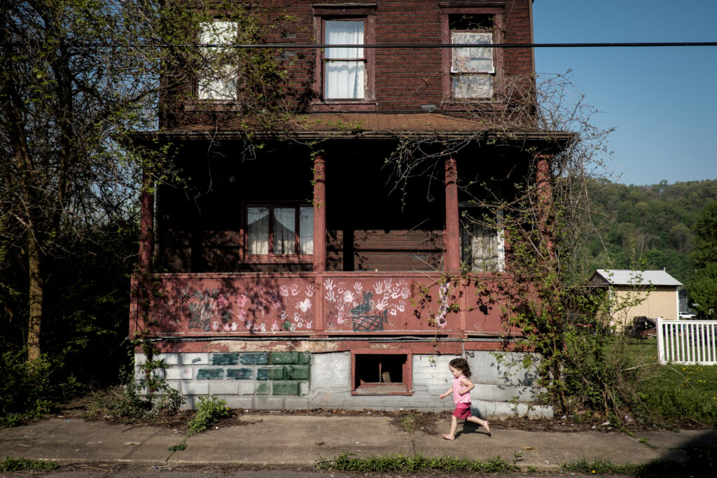 A young girl runs past an old J&L company home that is slated in West Aliquippa, Pennsylvania. (By Pete Marovich)
